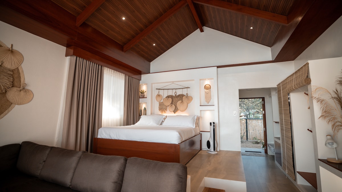 Villa bedroom interior with king-size bed, vaulted wooden ceiling, and boho decor